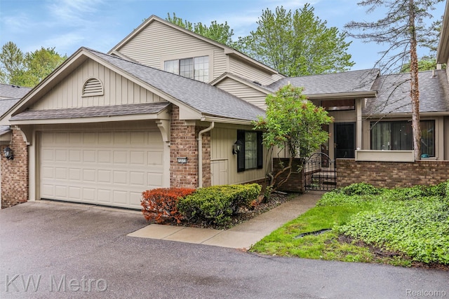 7273 Creeks Bend Ct, West Bloomfield, MI 48322 - view of front facade with roof with shingles, brick siding, an attached garage, driveway, and a gate