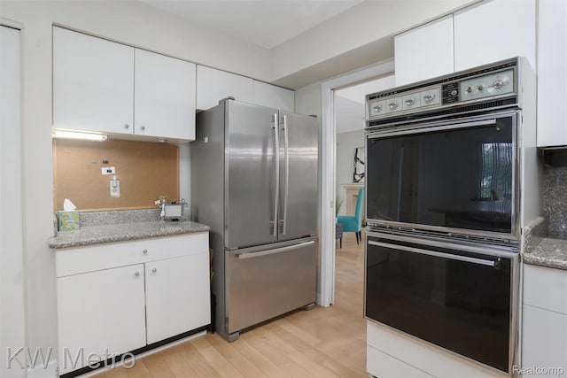 7273 Creeks Bend Ct, West Bloomfield, MI 48322 - kitchen featuring freestanding refrigerator, double wall oven, light wood-style flooring, white cabinetry, and light stone counters