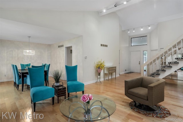 7273 Creeks Bend Ct, West Bloomfield, MI 48322 - living area featuring high vaulted ceiling, track lighting, wood finished floors, stairs, and a chandelier