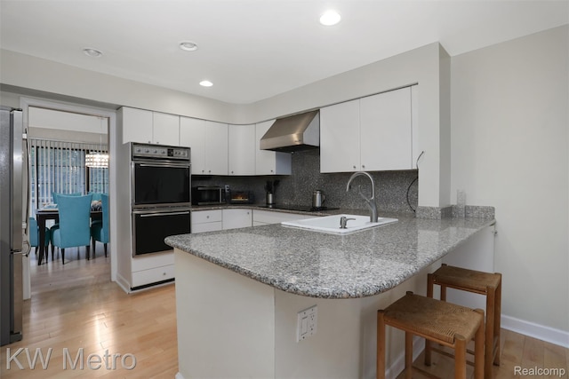 7273 Creeks Bend Ct, West Bloomfield, MI 48322 - kitchen with wall chimney exhaust hood, multiple ovens, a peninsula, freestanding refrigerator, and a sink