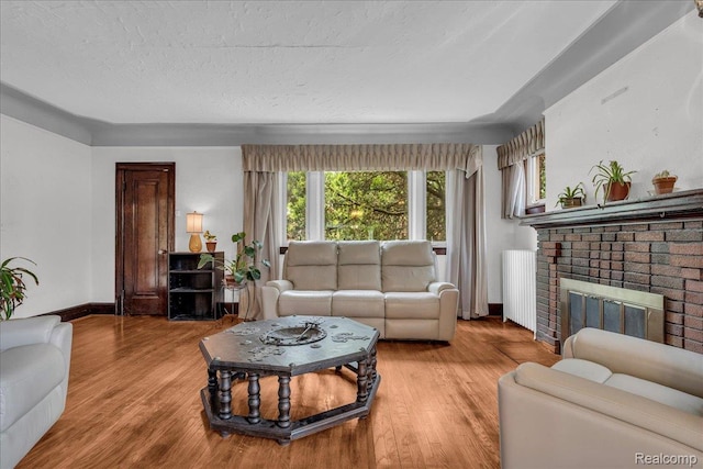 14004 Abington Ave, Detroit, MI 48227 - living area featuring plenty of natural light, light wood finished floors, a brick fireplace, and a textured ceiling