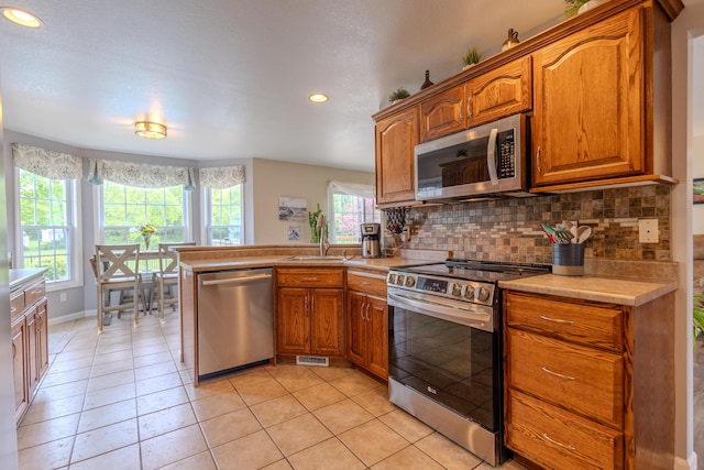 6573 Sweet Clover Hills Dr, Jonesville, MI 49250 - kitchen featuring stainless steel appliances, a sink, a peninsula, brown cabinetry, and recessed lighting
