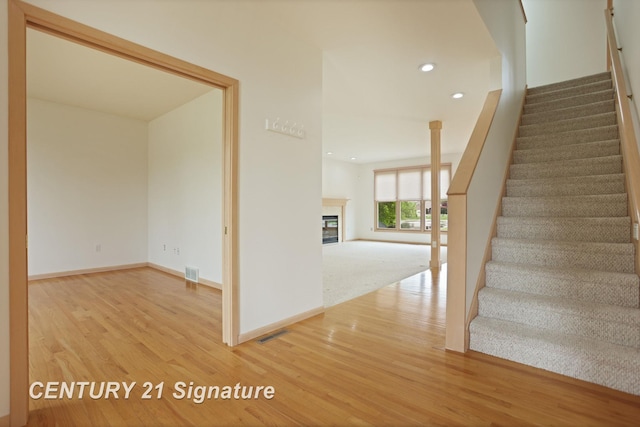 3803 Prairie Creek St, Saginaw, MI 48603 - stairway featuring wood finished floors, baseboards, a glass covered fireplace, and recessed lighting