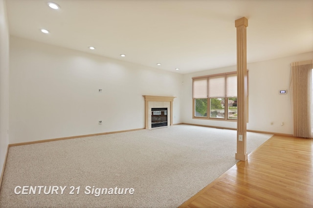3803 Prairie Creek St, Saginaw, MI 48603 - unfurnished living room with baseboards, a fireplace with flush hearth, recessed lighting, light colored carpet, and light wood-style flooring