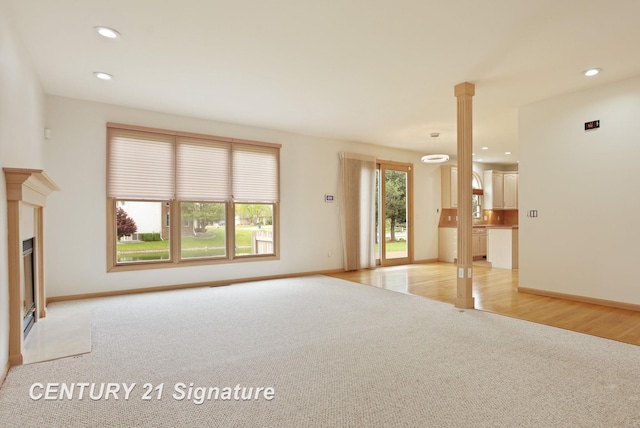 3803 Prairie Creek St, Saginaw, MI 48603 - unfurnished living room with light carpet, recessed lighting, baseboards, a fireplace with flush hearth, and decorative columns