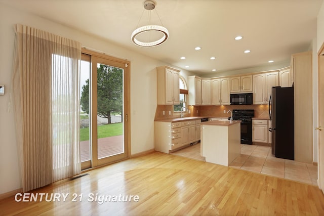 3803 Prairie Creek St, Saginaw, MI 48603 - kitchen featuring black appliances, a kitchen island with sink, a sink, tasteful backsplash, and light wood-style floors