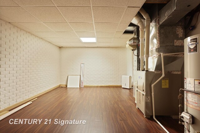 3803 Prairie Creek St, Saginaw, MI 48603 - finished basement featuring a paneled ceiling, brick wall, wood finished floors, baseboards, and heating unit