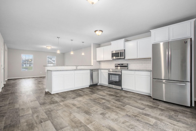 13670 Oasis Ave, Holland, MI 49424 - kitchen with appliances with stainless steel finishes, a peninsula, wood finished floors, tasteful backsplash, and white cabinets