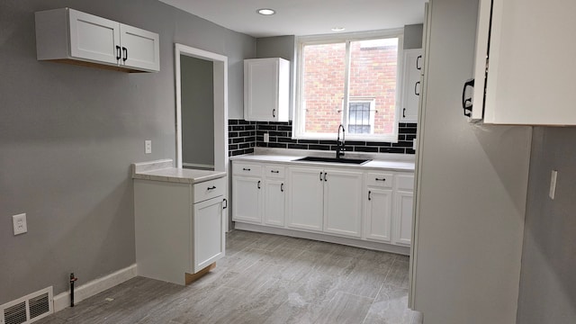 15465 Murray Hl, Detroit, MI 48227 - kitchen with a sink, tasteful backsplash, baseboards, white cabinets, and light countertops