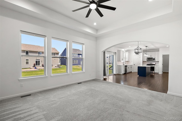 24603 Beach Dr, Macomb, MI 48042 - unfurnished living room with arched walkways, dark colored carpet, ceiling fan, recessed lighting, and a raised ceiling