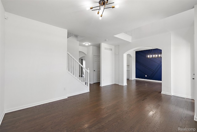 24603 Beach Dr, Macomb, MI 48042 - unfurnished living room featuring a chandelier, arched walkways, stairway, wood finished floors, and baseboards