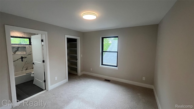 206 E Windemere Ave, Royal Oak, MI 48073 - unfurnished bedroom with multiple windows, a walk in closet, baseboards, and carpet