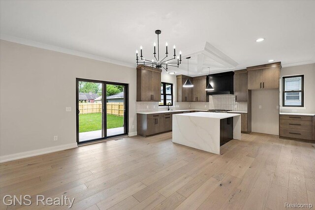 206 E Windemere Ave, Royal Oak, MI 48073 - kitchen featuring custom exhaust hood, a chandelier, a kitchen island, ornamental molding, and decorative backsplash