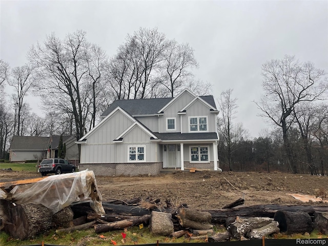 10705 Deer Ridge Trl, Rose, MI 48442 - view of front of house with board and batten siding, a shingled roof, and brick siding