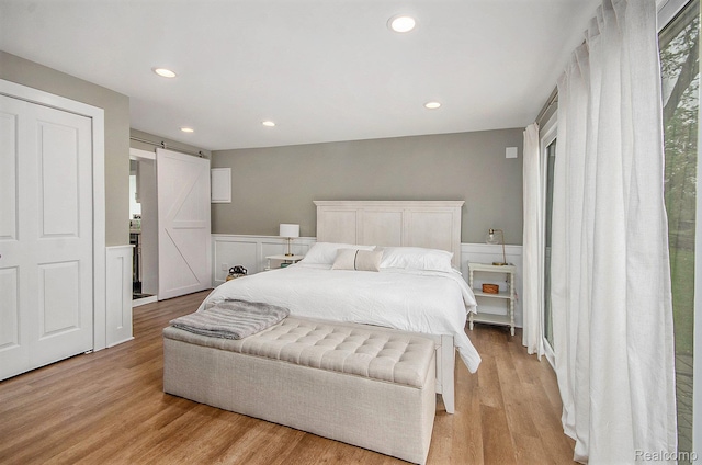 35274 Lake Dr, Brownstown, MI 48173 - bedroom with a barn door, a wainscoted wall, light wood-type flooring, recessed lighting, and a decorative wall