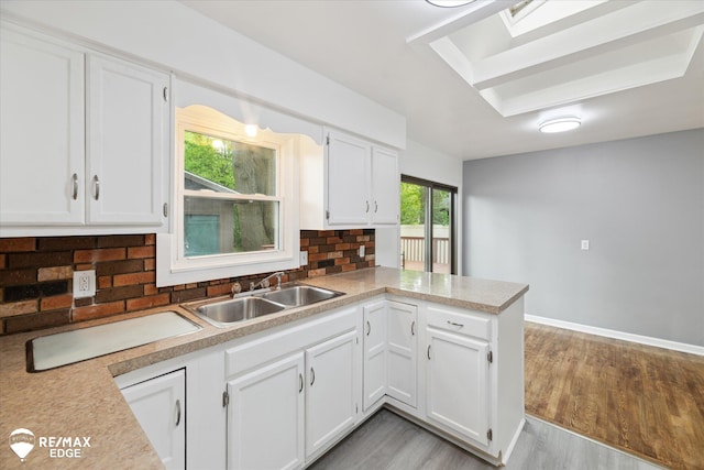 3825 Craig Dr, Flint, MI 48506 - kitchen with a sink, decorative backsplash, white cabinets, a peninsula, and light countertops