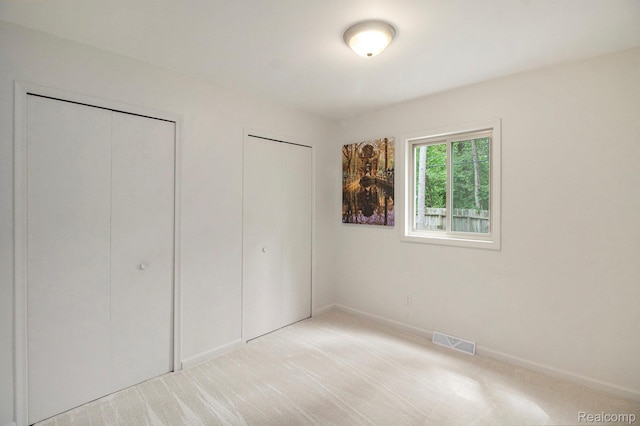 7831 Caberfae Trl, Clarkston, MI 48348 - unfurnished bedroom with light colored carpet, two closets, and baseboards