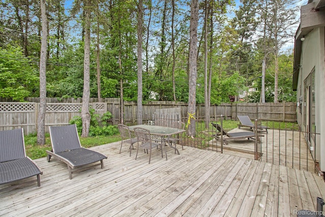 7831 Caberfae Trl, Clarkston, MI 48348 - wooden deck featuring outdoor dining space, a fenced backyard, and view of scattered trees