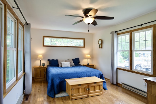 8595 E Napier Ave, Benton Harbor, MI 49022 - bedroom with baseboard heating, light wood finished floors, a barn door, a ceiling fan, and baseboards
