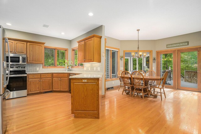 8837 56th Ave, Hudsonville, MI 49426 - kitchen with appliances with stainless steel finishes, light wood finished floors, brown cabinets, healthy amount of natural light, and recessed lighting