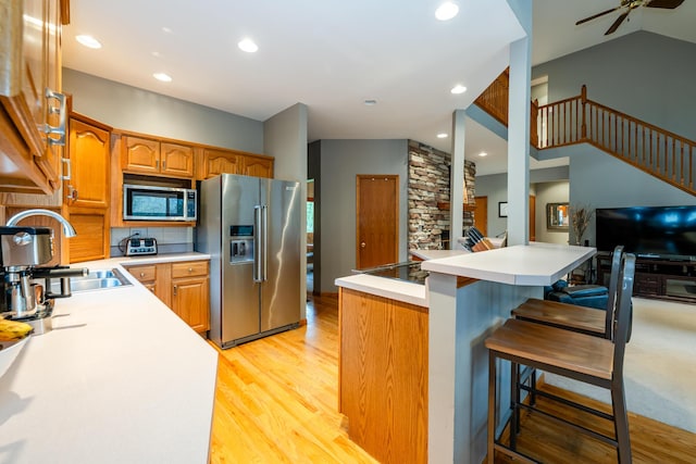 4569 Terra Ln, Saint Joseph, MI 49085 - kitchen featuring stainless steel appliances, light wood-type flooring, a breakfast bar area, light countertops, and vaulted ceiling