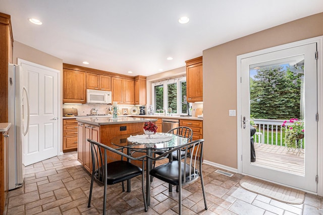 2176 Teal Ct SE, Grand Rapids, MI 49546 - kitchen with white appliances, stone tile flooring, a center island, decorative backsplash, and recessed lighting