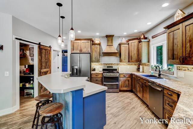 1109 Kenowa Ave SW, Byron Center, MI 49315 - kitchen featuring appliances with stainless steel finishes, custom range hood, a barn door, a sink, and light wood-style floors