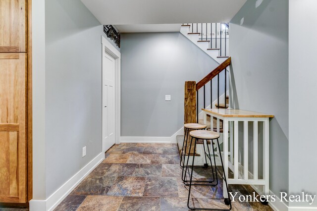 1109 Kenowa Ave SW, Byron Center, MI 49315 - foyer entrance with dark stone finish flooring, baseboards, and stairs