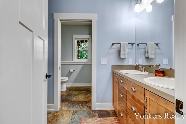 1109 Kenowa Ave SW, Byron Center, MI 49315 - bathroom with stone tile flooring, baseboards, double vanity, and toilet