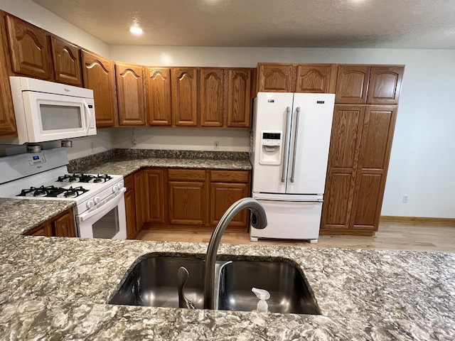 5764 W Brookwood Pl, Ludington, MI 49431 - kitchen featuring white appliances, a sink, dark stone countertops, and brown cabinets