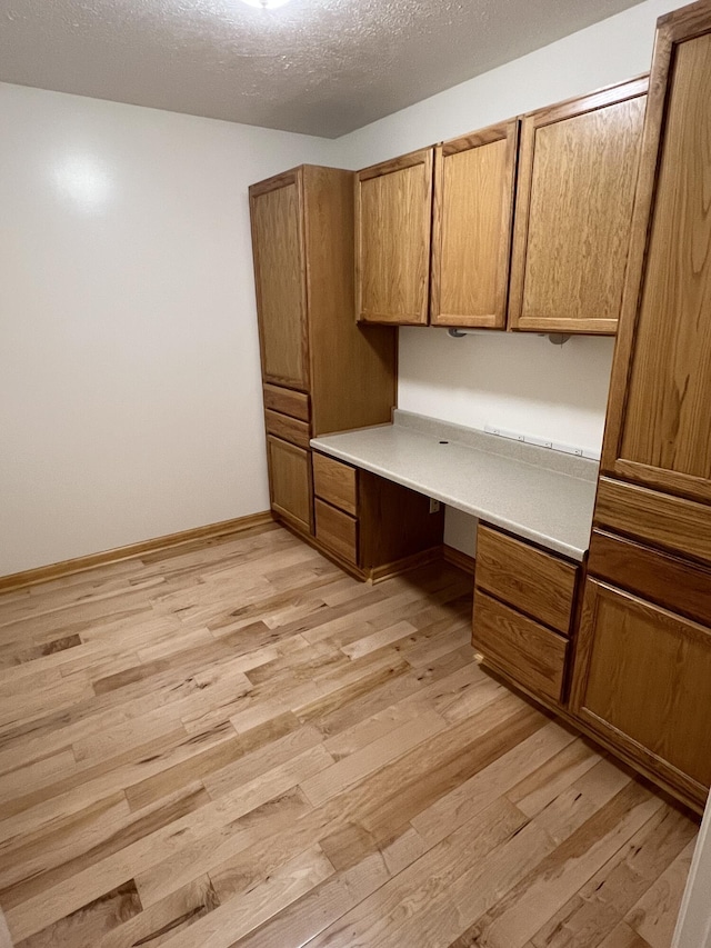 5764 W Brookwood Pl, Ludington, MI 49431 - unfurnished office featuring built in study area, light wood-style flooring, and a textured ceiling