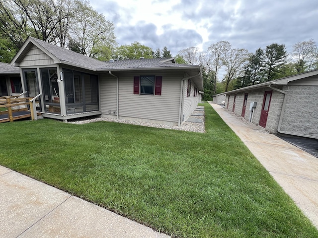 5764 W Brookwood Pl, Ludington, MI 49431 - view of front facade featuring a sunroom, a shingled roof, and a front yard