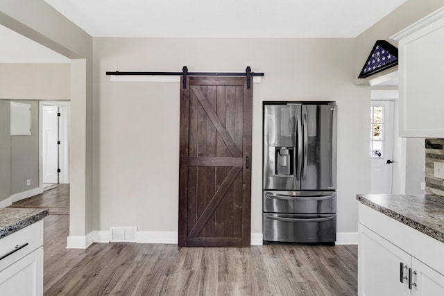 4371 N 68th Ave, Hart, MI 49420 - kitchen with stainless steel fridge with ice dispenser, light wood-style floors, white cabinetry, and baseboards