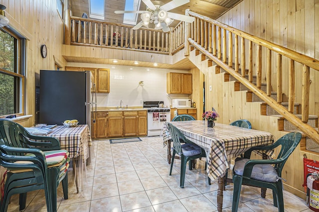 4900 N Railroad Ave, Pentwater, MI 49449 - kitchen with white appliances, a sink, wooden walls, a high ceiling, and a ceiling fan
