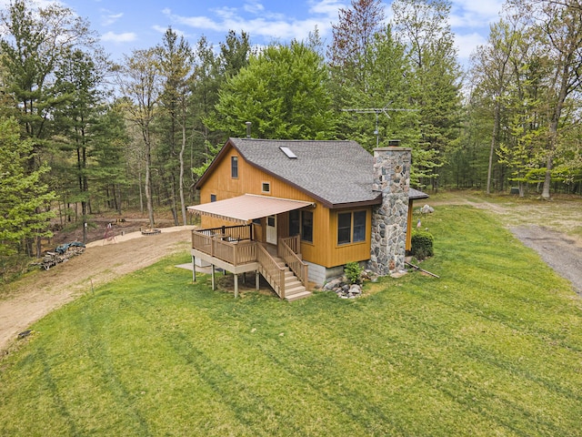 4900 N Railroad Ave, Pentwater, MI 49449 - view of front of property featuring a chimney, a front yard, roof with shingles, a forest view, and stairs