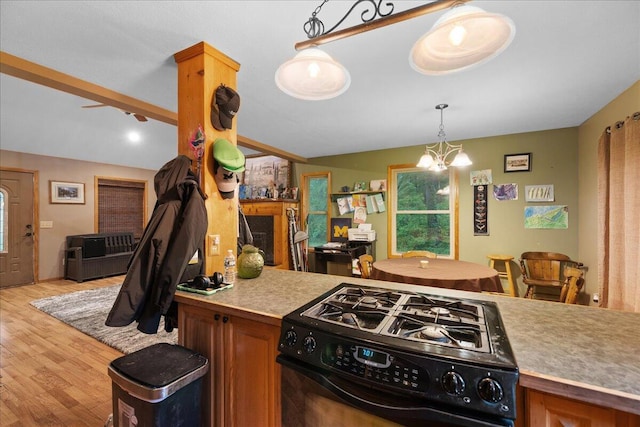 65 N Brown Rd, Bailey, MI 49303 - kitchen featuring black range with gas stovetop, light wood-style flooring, a chandelier, brown cabinetry, and lofted ceiling