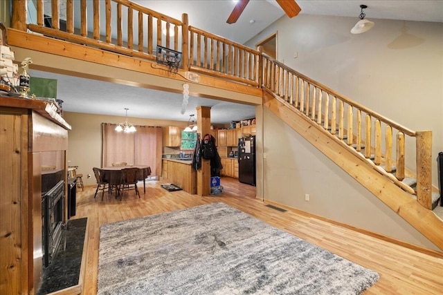 65 N Brown Rd, Bailey, MI 49303 - living area featuring light wood-type flooring, stairs, high vaulted ceiling, a ceiling fan, and a fireplace with raised hearth