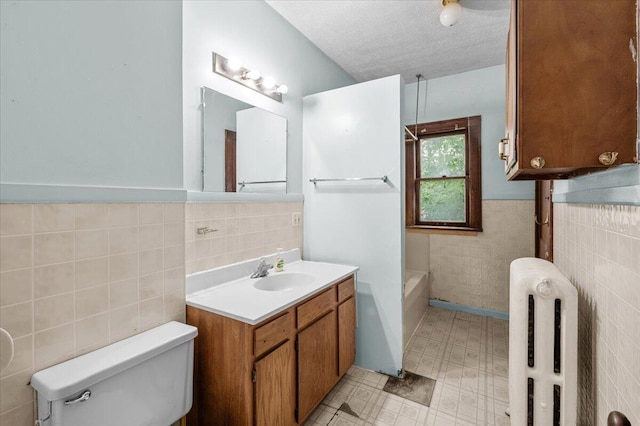 1019 Second St NW, Grand Rapids, MI 49504 - full bathroom featuring tile walls, radiator, toilet, vanity, and a textured ceiling