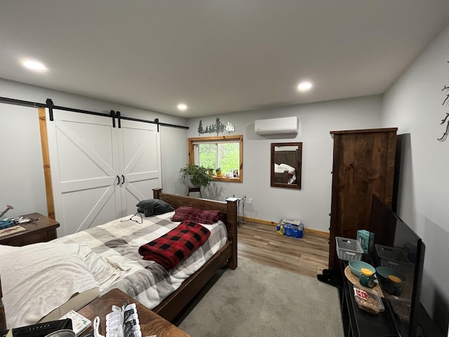 550 E N St, Edmore, MI 48829 - bedroom with a wall mounted AC, a barn door, wood finished floors, recessed lighting, and baseboards