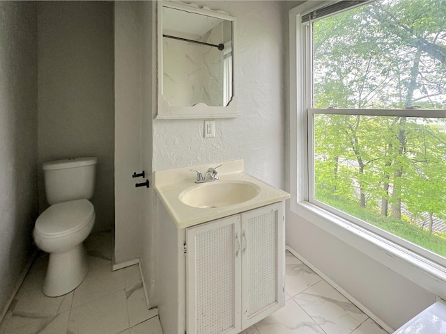 93 Goguac St E, Battle Creek, MI 49015 - bathroom with vanity, toilet, healthy amount of natural light, and baseboards