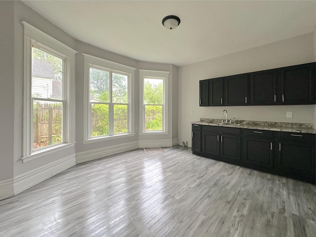 93 Goguac St E, Battle Creek, MI 49015 - kitchen with dark cabinets, a sink, light wood-style flooring, and baseboards