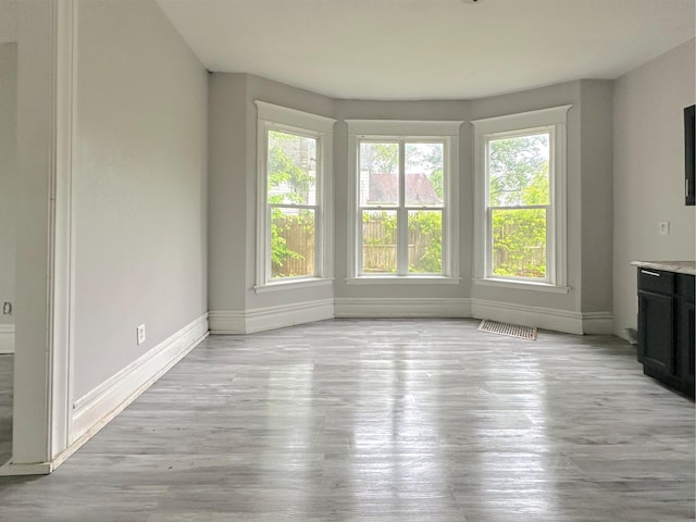93 Goguac St E, Battle Creek, MI 49015 - unfurnished dining area featuring baseboards and light wood-style flooring