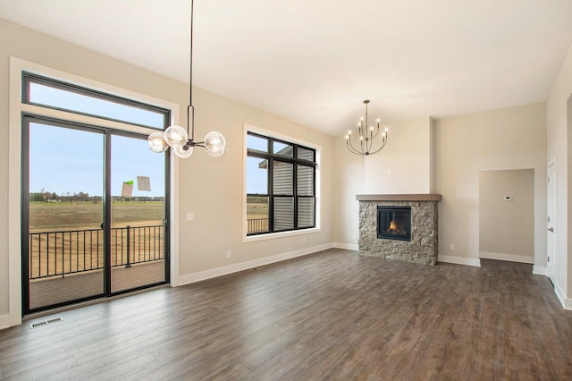 0 Baldwin St, Hudsonville, MI 49426 - unfurnished living room featuring a chandelier, dark wood-type flooring, a stone fireplace, and baseboards