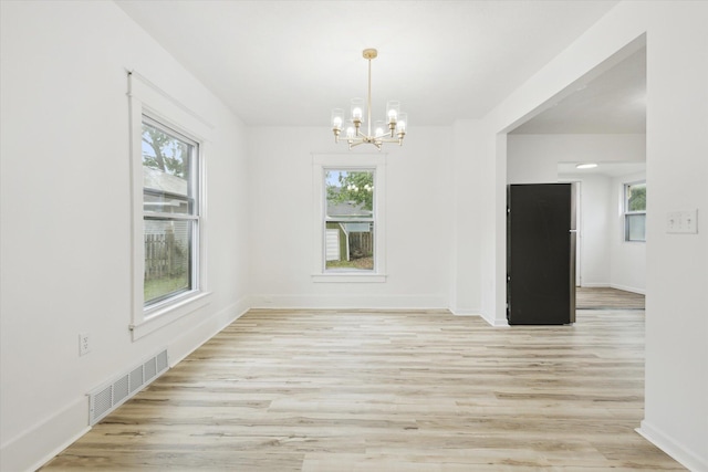 2218 Dalton Ave SW, Wyoming, MI 49519 - empty room featuring a chandelier, healthy amount of natural light, light wood-style flooring, and baseboards