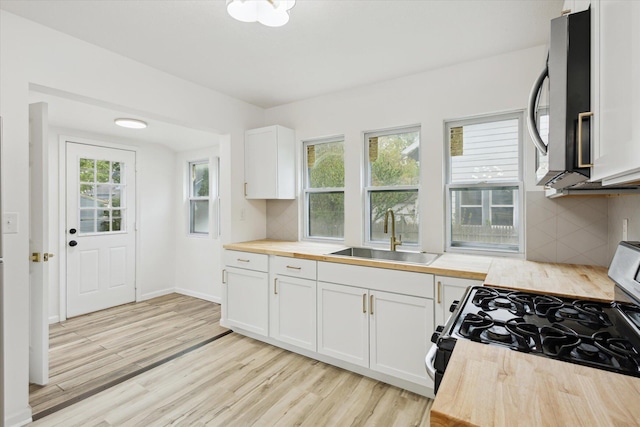2218 Dalton Ave SW, Wyoming, MI 49519 - kitchen with a sink, gas stove, wooden counters, stainless steel microwave, and decorative backsplash