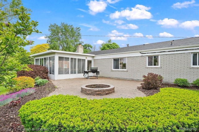 24018 Glen Ridge Ct, Novi, MI 48375 - back of house featuring a sunroom, an outdoor fire pit, a patio area, a chimney, and roof with shingles