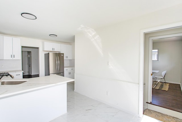 24548 Templar Ave, Southfield, MI 48075 - kitchen with freestanding refrigerator, a sink, light stone countertops, white cabinetry, and decorative backsplash