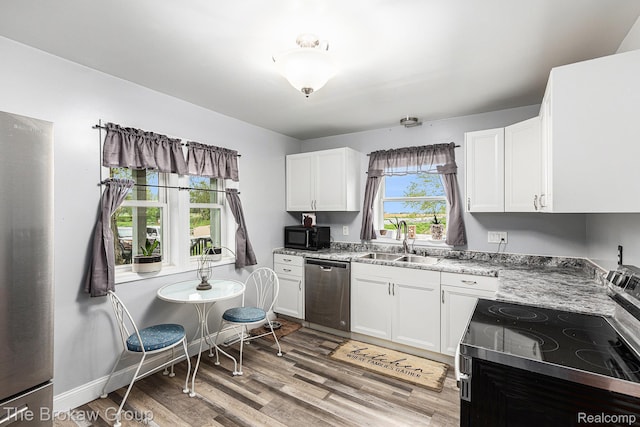 4470 Beach St, Akron, MI 48701 - kitchen featuring stainless steel appliances, a sink, white cabinetry, light wood-style flooring, and light stone counters