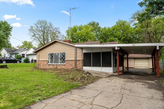 3301 S Kearsley Blvd, Flint, MI 48506 - view of home's exterior featuring driveway, a yard, a sunroom, brick siding, and an attached carport