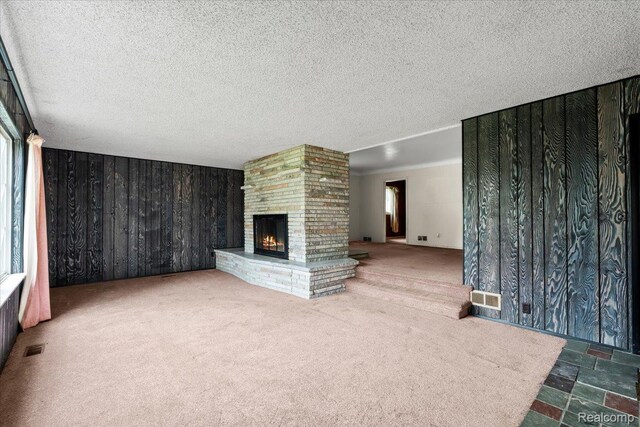 3301 S Kearsley Blvd, Flint, MI 48506 - unfurnished living room with a brick fireplace, wooden walls, plenty of natural light, carpet flooring, and a textured ceiling